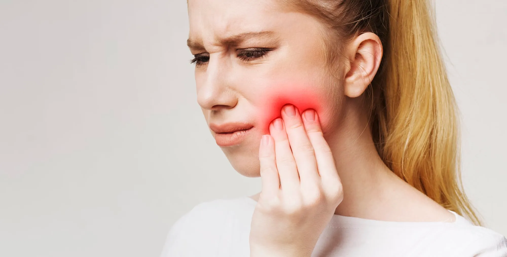 Un homme tenant sa joue, signe d'une douleur dentaire